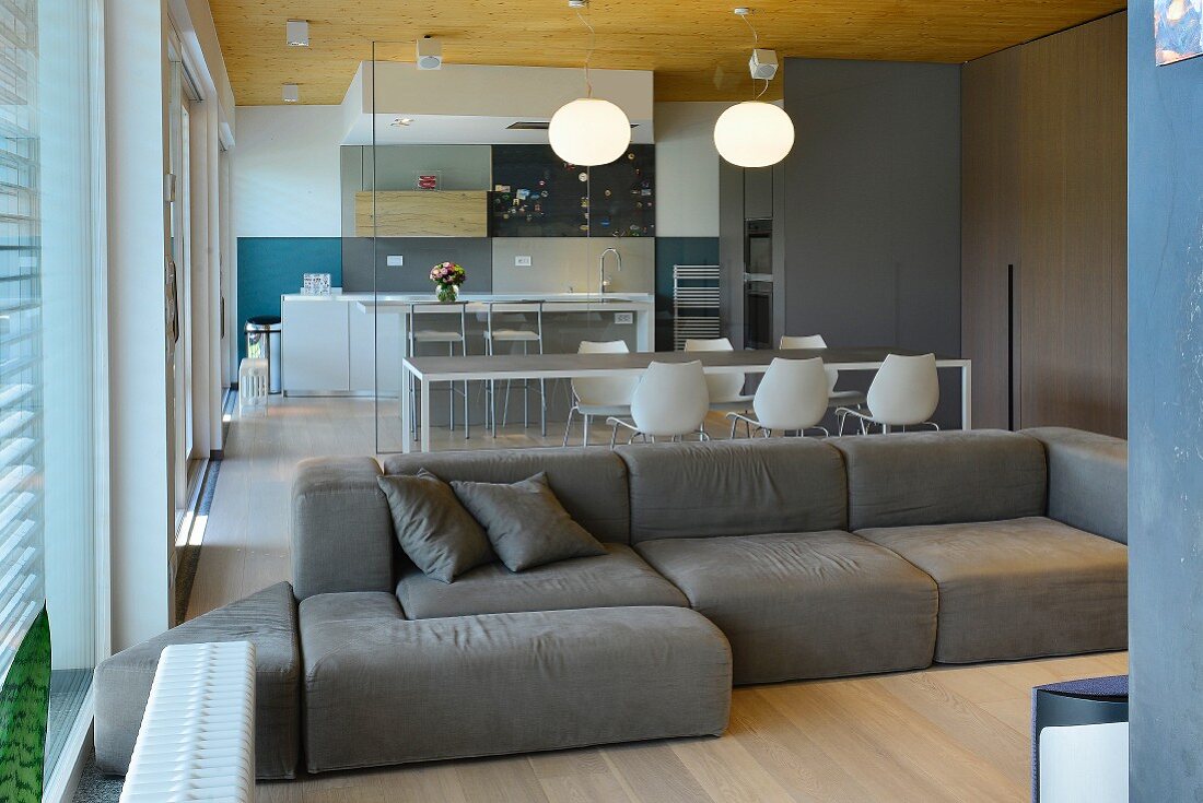 Gemütliches Loungesofa in offenem Designer-Wohnbereich mit Glasabtrennung zur Küche