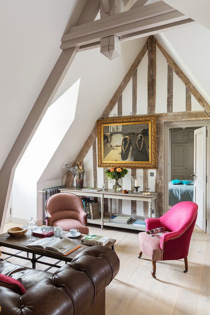 Loungebereich im Dachgeschoss mit pinkfarbenem Armlehnessel und Gemälde im Goldrahmen