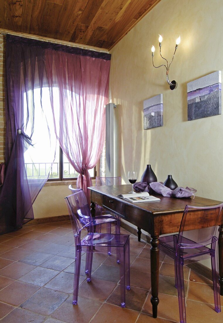 Mediterranean dining area with purple plexiglas chairs and accessories