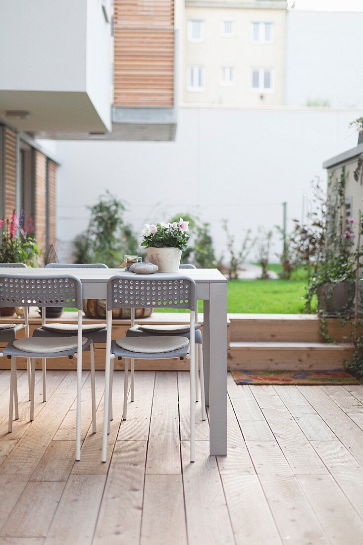 Tisch mit Stühlen auf Terrasse mit Holzboden im Hinterhof