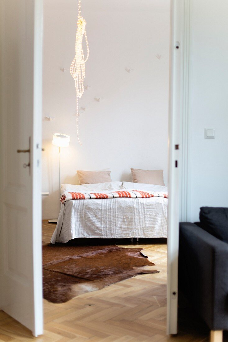 Cowhide rug and rope light in bedroom seen through open double doors
