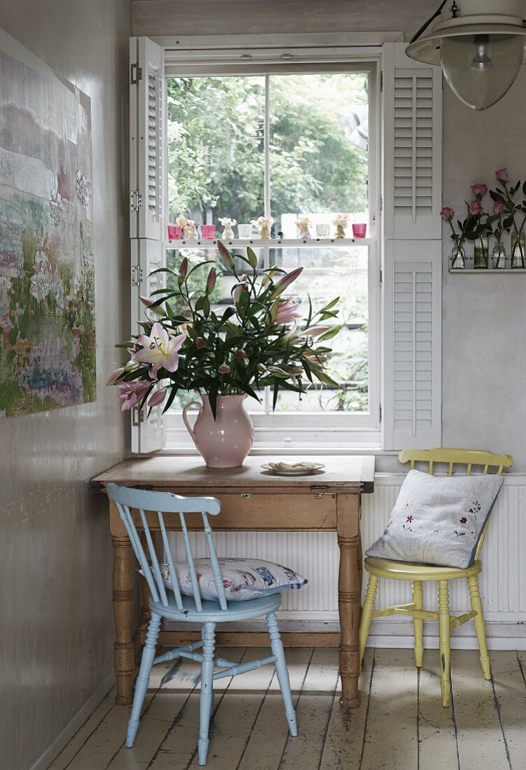 Küchenstühle an rustikalen Holztisch in Zimmerecke, vor Fenster mit geöffneten weissen Fensterläden