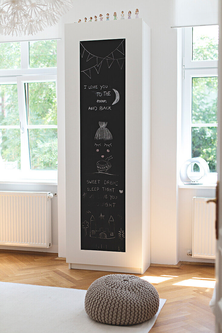 Simple white wardrobe with chalkboard door flanked by windows