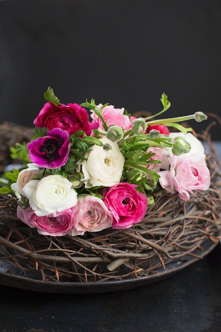 Bouquet of pink and white ranunculus and anemones on twig wreath