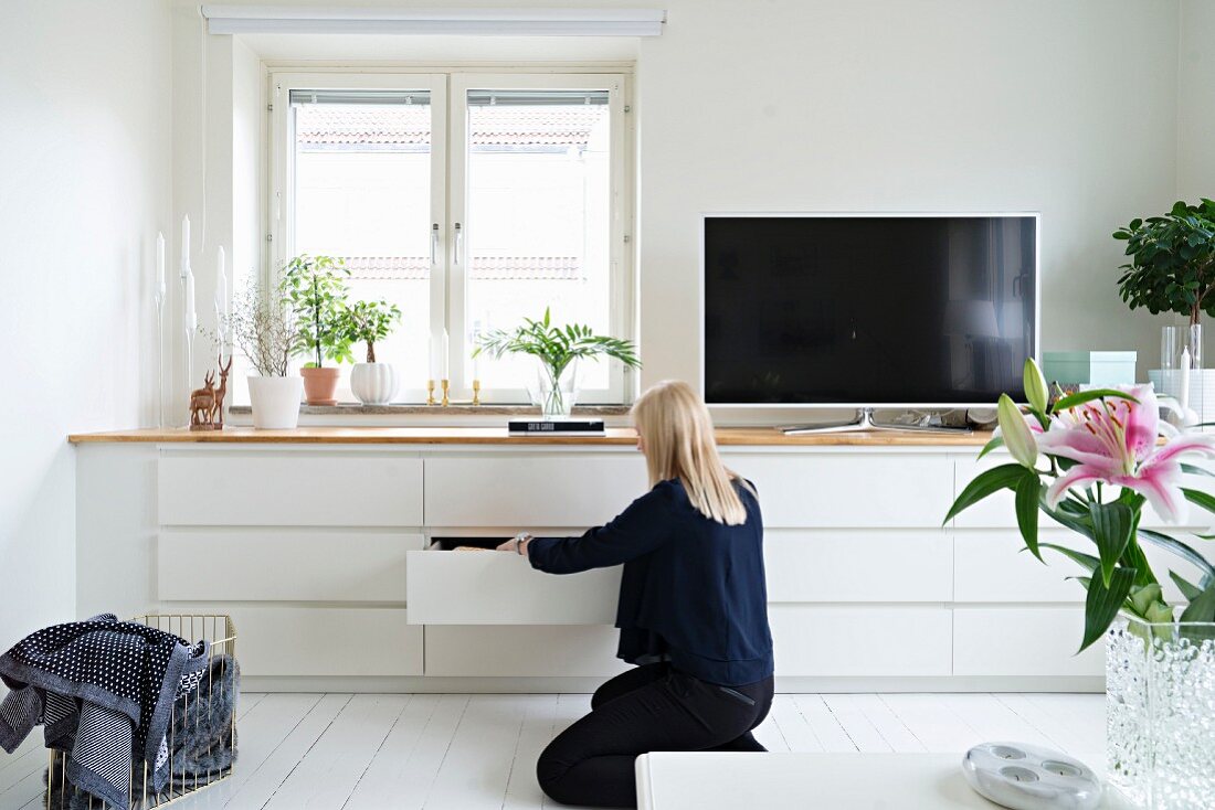 Woman in front of white fitted sideboard with drawers and flatscreen TV