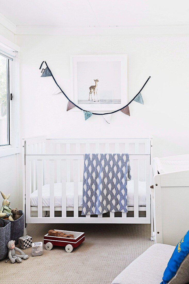 Bright children's room with white crib, toys and pennant chain as wall decoration
