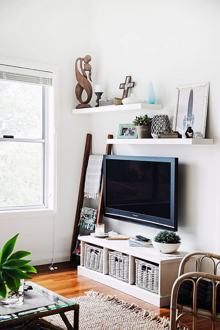 Wohnzimmerecke mit aufgehängtem Fernseher über Sideboard mit Körben