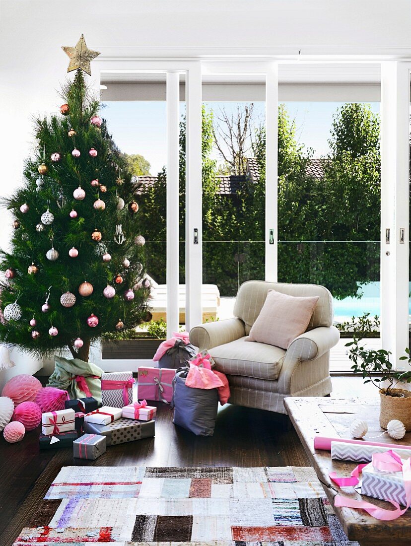 Australian living room with decorated Christmas tree, wrapped gifts and cozy upholstered armchair