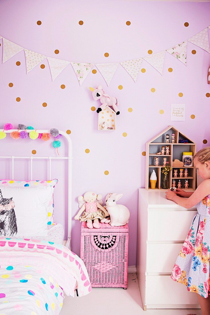 Mädchen im rosafarbenen Kinderzimmer mit gepunkteter Wand