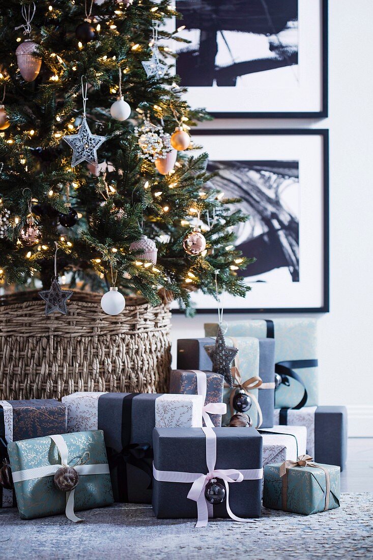 Verpackte Weihnachtsgeschenke unter beleuchtetem, geschmücktem Weihnachtsbaum