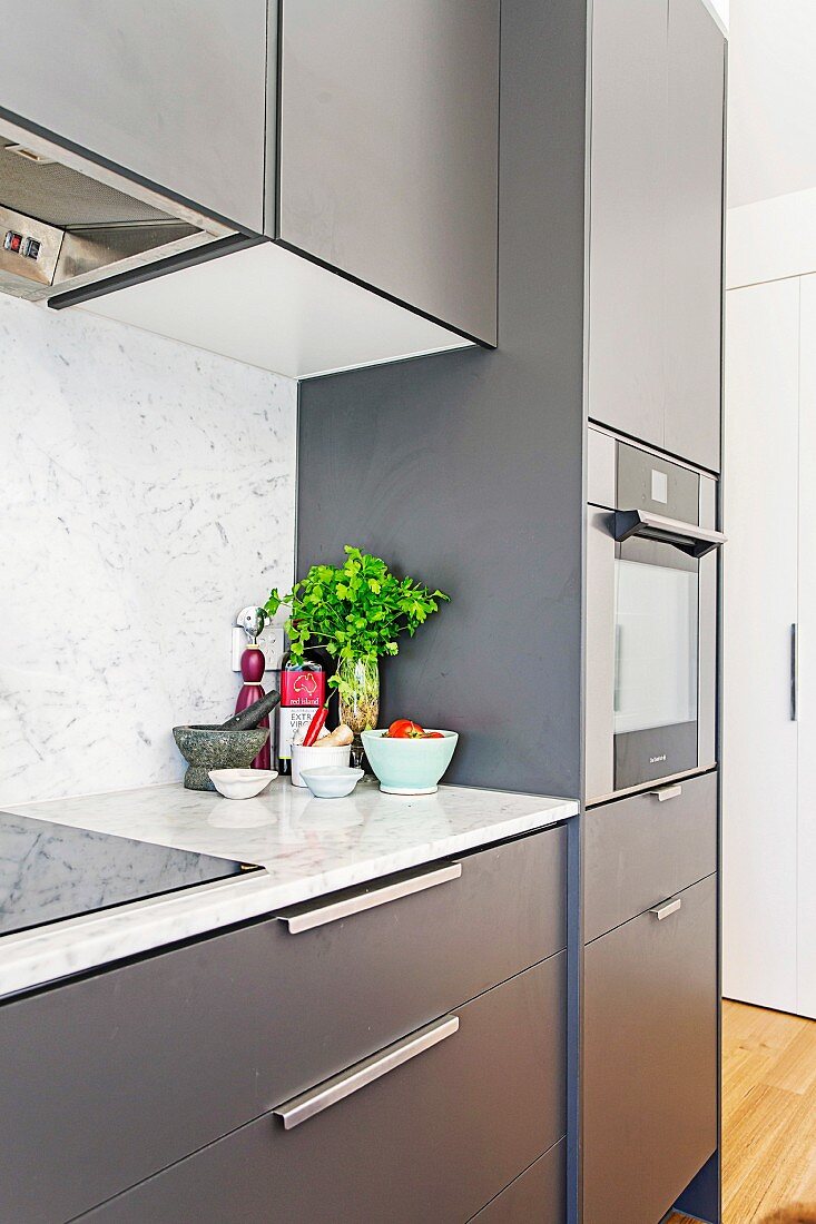 Blick auf anthrazitfarbene Küchenzeile mit Marmor-Küchenarbeitsplatte und Spritzschutz