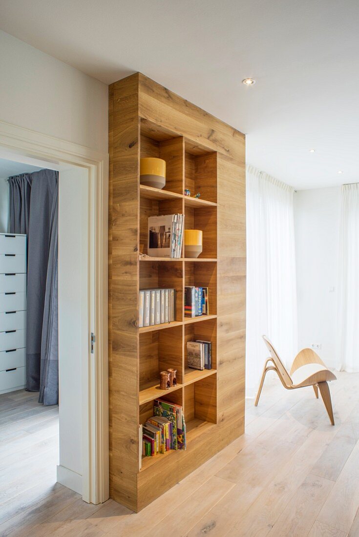 Open-fronted, floor-to-ceiling fitted bookcase in minimalist living area