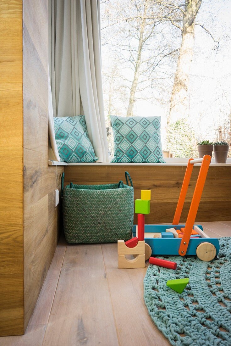 Holzverkleidete moderne Zimmerecke mit Eichenboden, Fenstersitzbank und Holzspielzeug