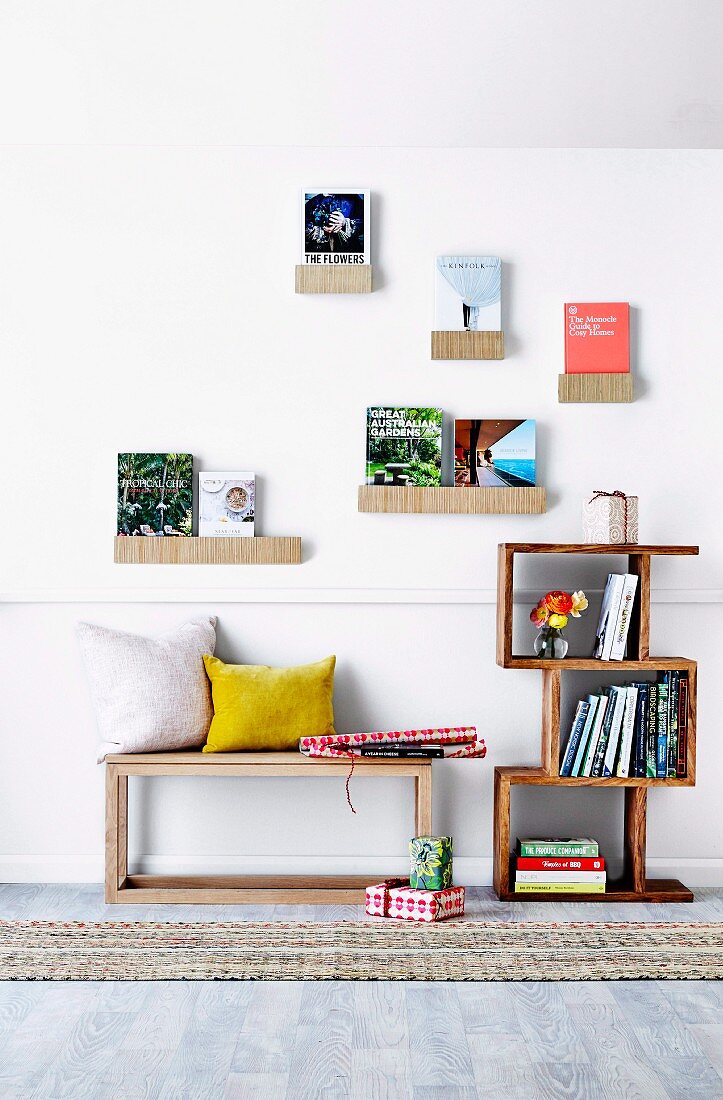 Decorative wall shelves with books on wooden bench and bookcase