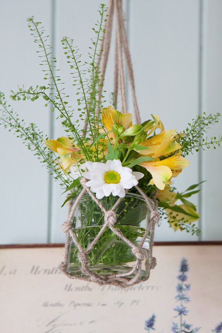 Glass vase of flowers in macrame hanger