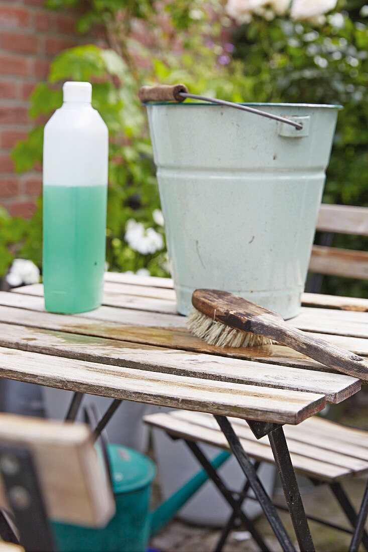 Spring cleaning a terrace with a vintage metal bucket and cleaning on a garden table