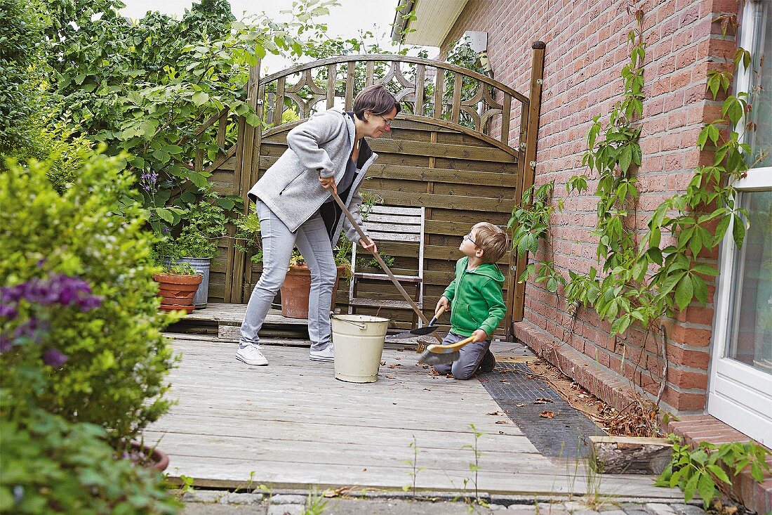 Frau mit Sohn beim Saubermachen der Terrasse