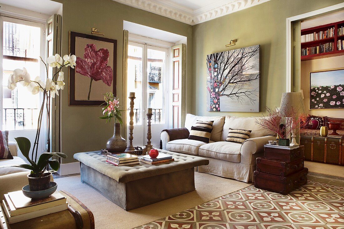 Künstlerisches Wohnzimmer mit gepolstertem Couchtisch, alten Koffern als Beistelltisch und Zementfliesen