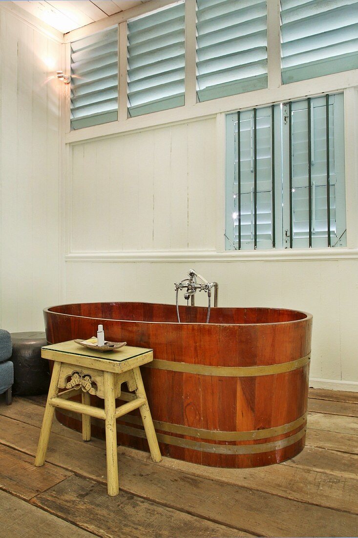 Free-standing wooden bathtub with Oriental stool as side table