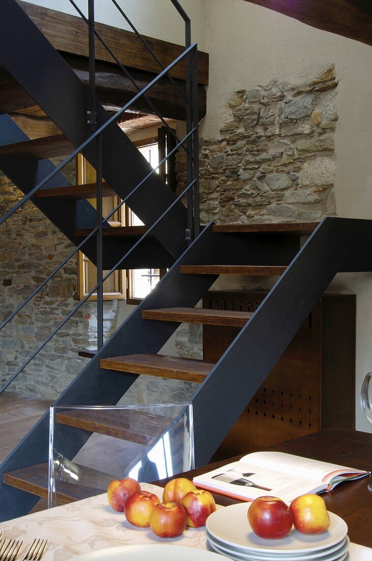 Eine moderne Treppe aus Holz und Metall an einer Natursteinwand