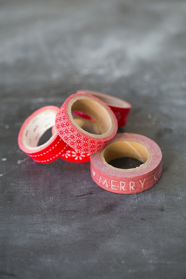 Several rolls of red, patterned washi tape on grey surface
