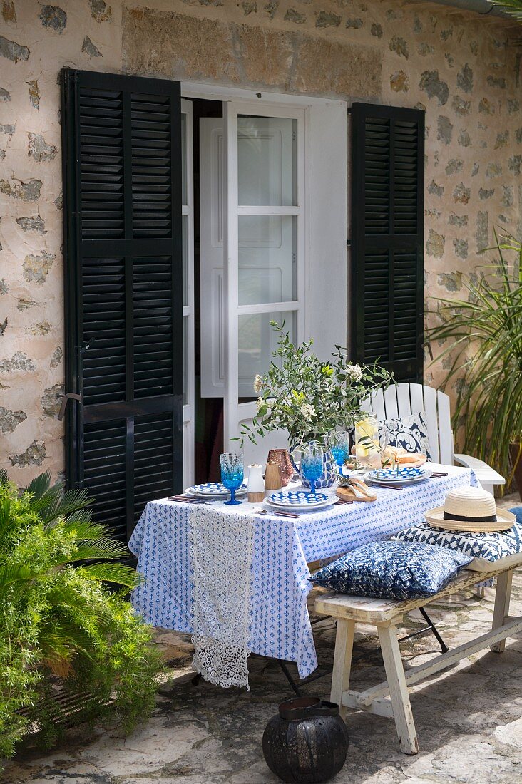 Set, summer dining table on terrace outside Mediterranean house