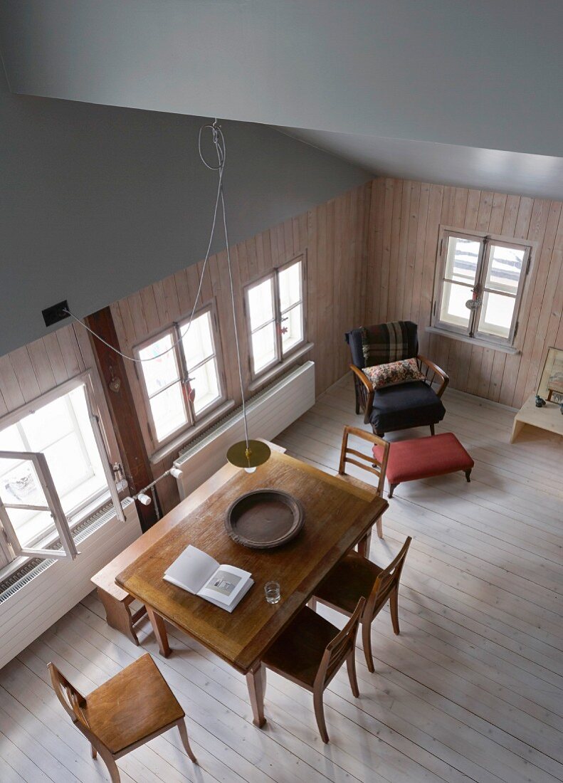 View down into renovated dining room in old wooden house with open sloping roof