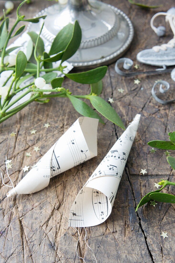 Sheet-music cones and sprigs of mistletoe on rustic wooden surface