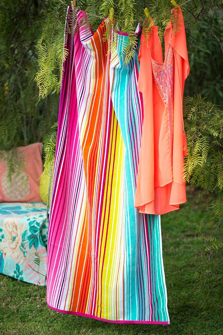 Tunic and striped towel hung from washing line in garden
