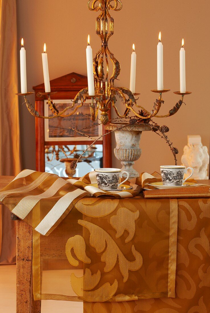 Herbstliche Tischdekoration mit goldfarbenen Tischläufern und Kronleuchter mit brennenden Kerzen