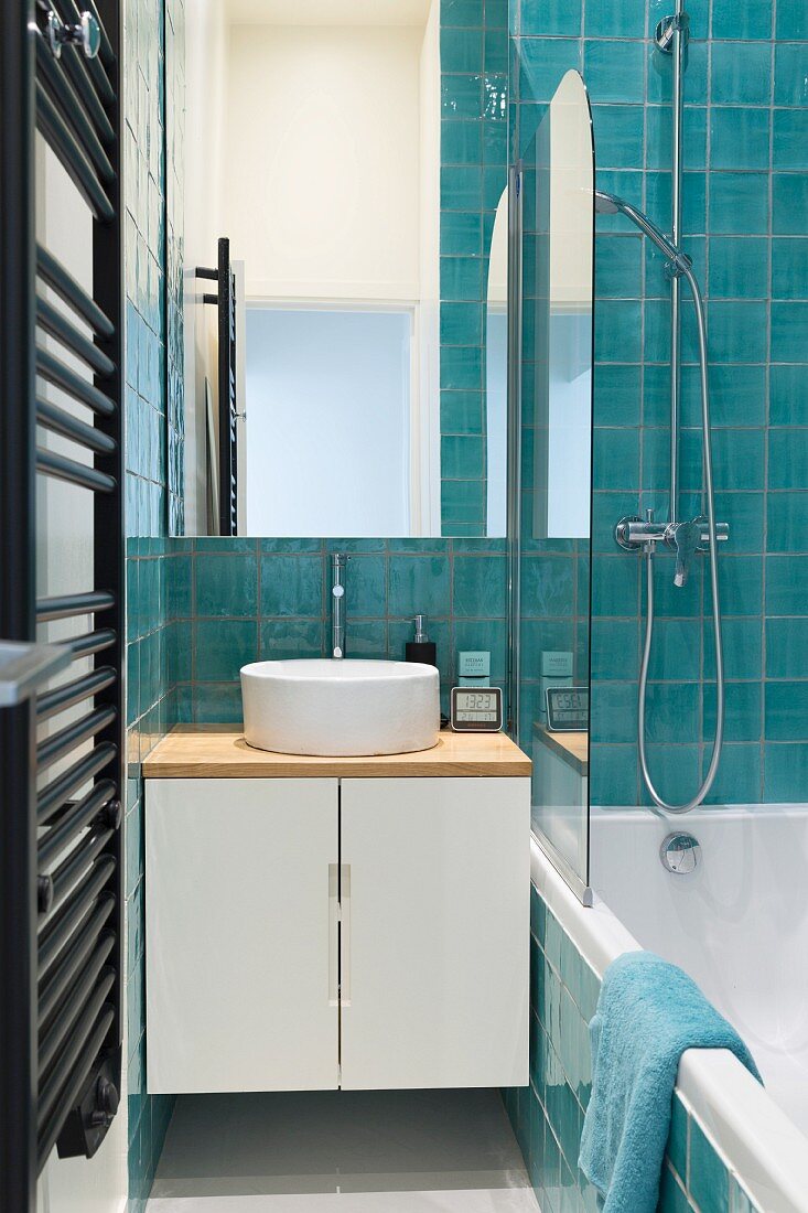 Bathtub and turquoise tiles in narrow bathroom