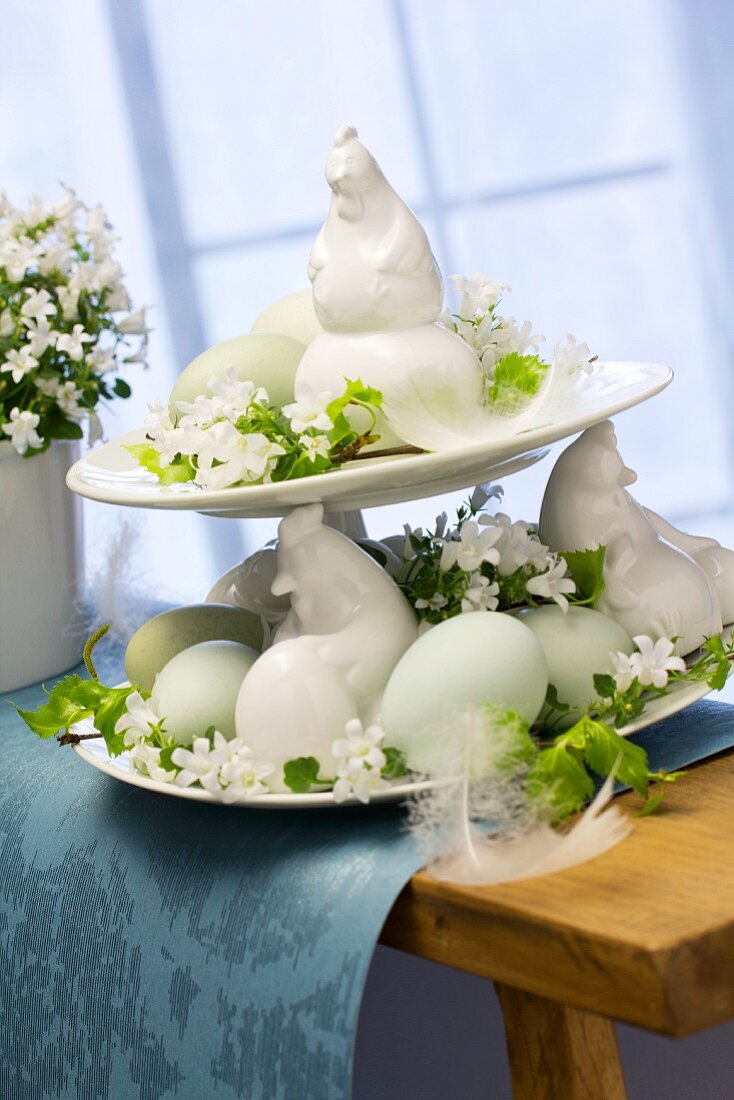 China hens, Easter eggs, white campanula and birch leaves on cake stand