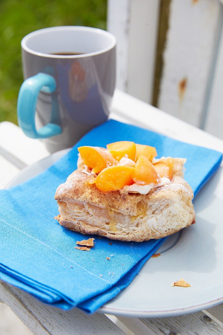Danish pastry with apricots and blue napkin on plate