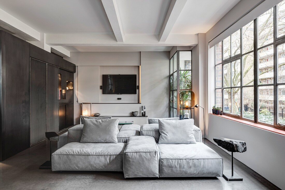 Sofa combination and factory windows in industrial loft apartment in shades of grey