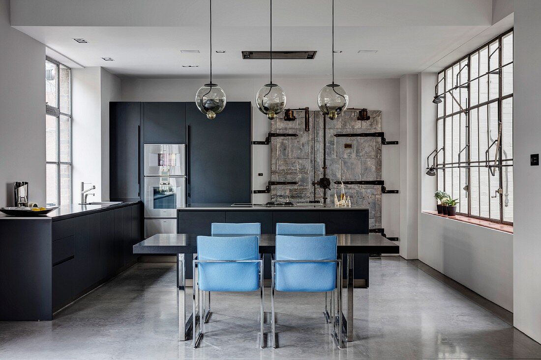 Offene Küche mit Esstisch und blauen Stühlen im Industrie-Loft in Grautönen