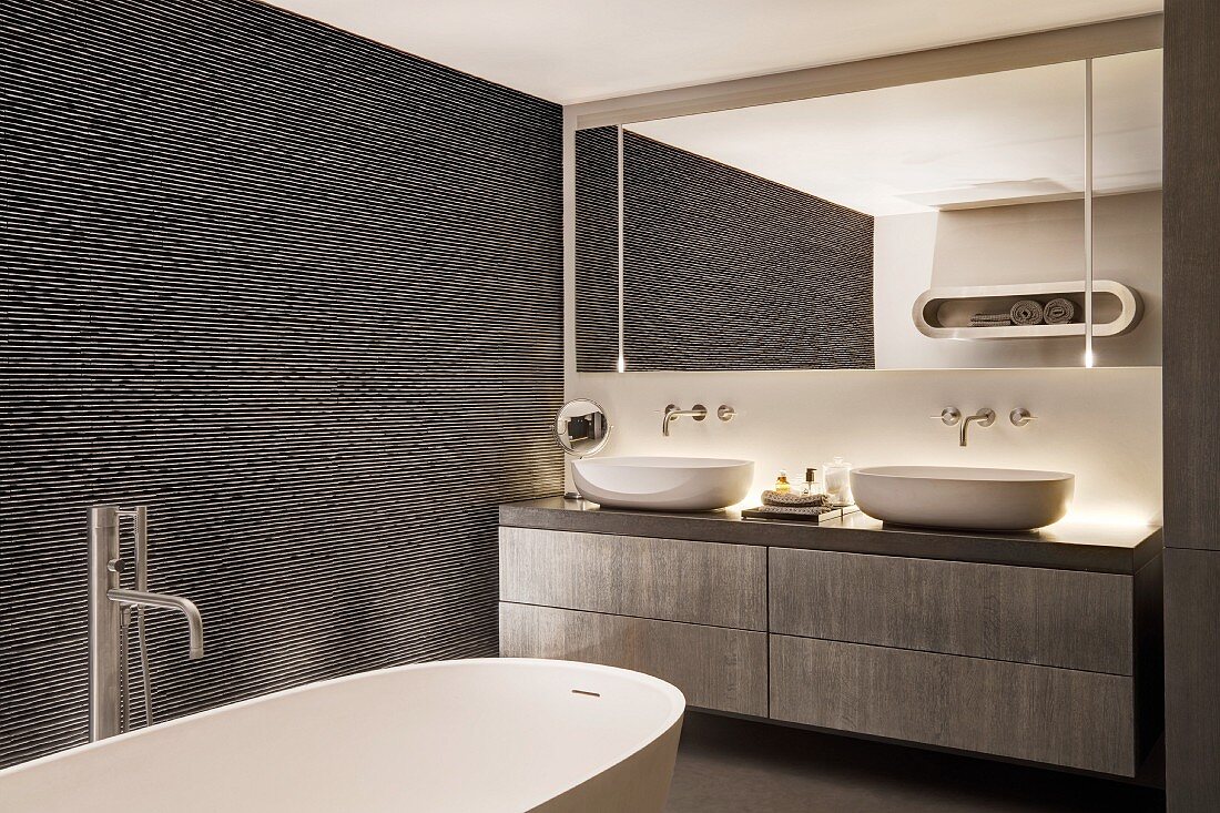 Oval bathtub and ival sinks in modern bathroom in shades of grey