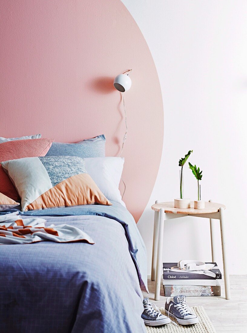 Modern bedroom with a pink circle painted on the wall as the head of the bed