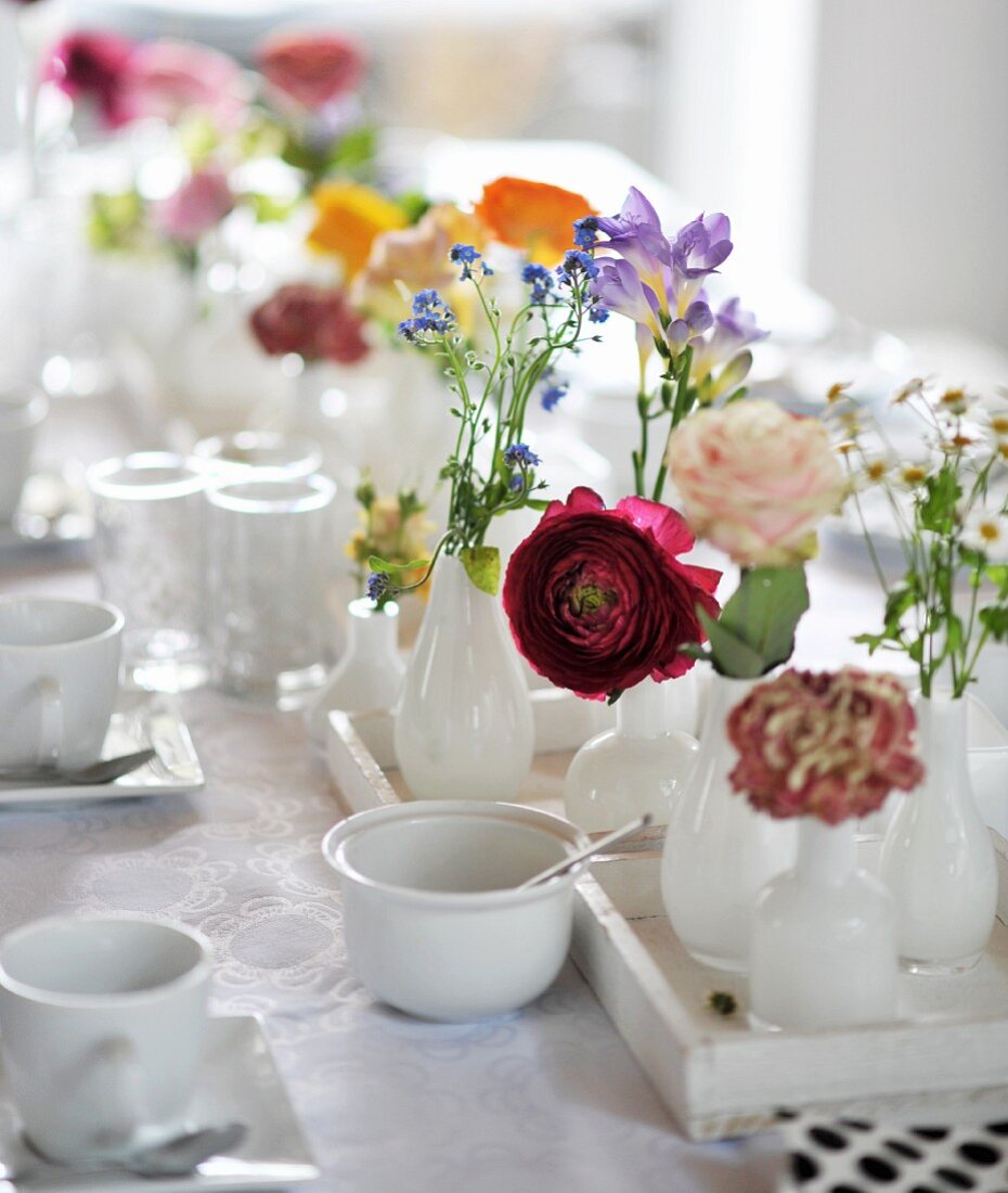 Gedeckter Tisch mit weißem Geschirr und Frühlingsblumen
