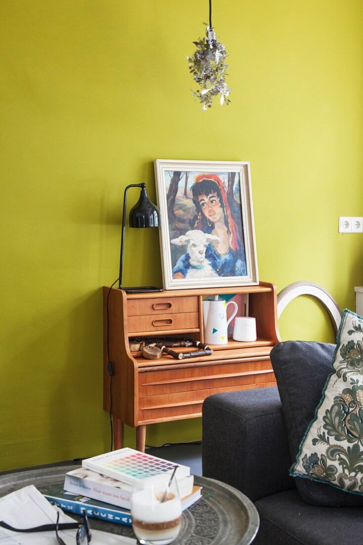 Picture on top of retro writing desk against mustard-yellow wall