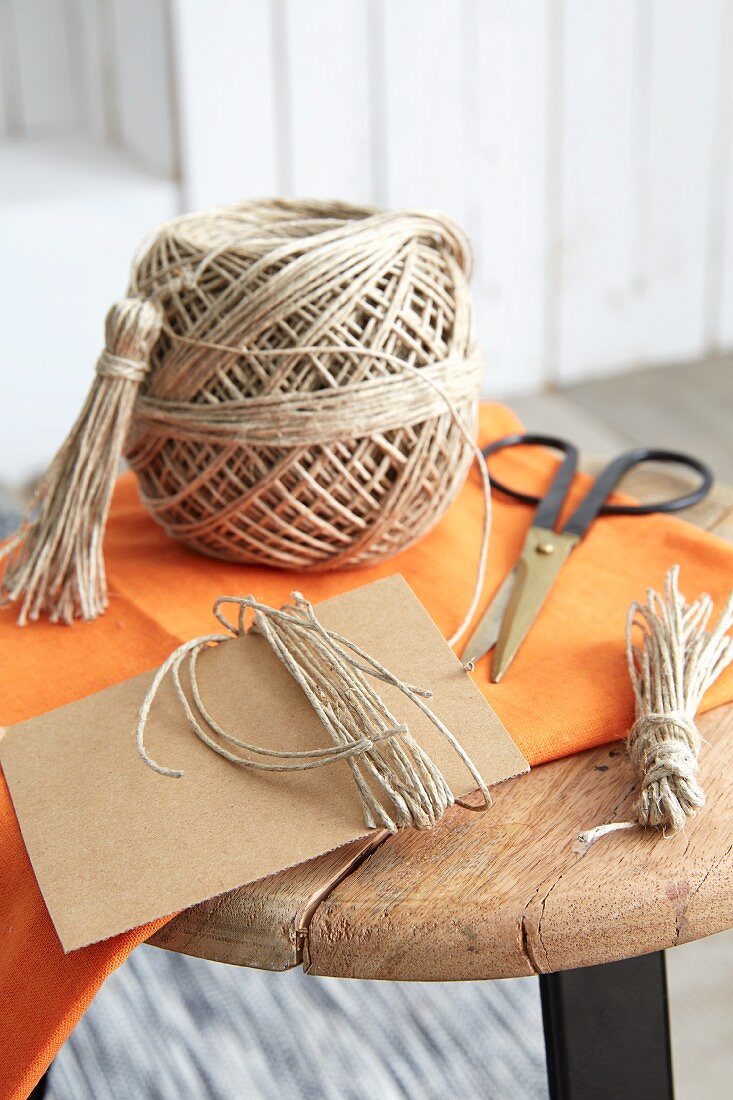 Parcel string, cardboard and scissors for making tassels