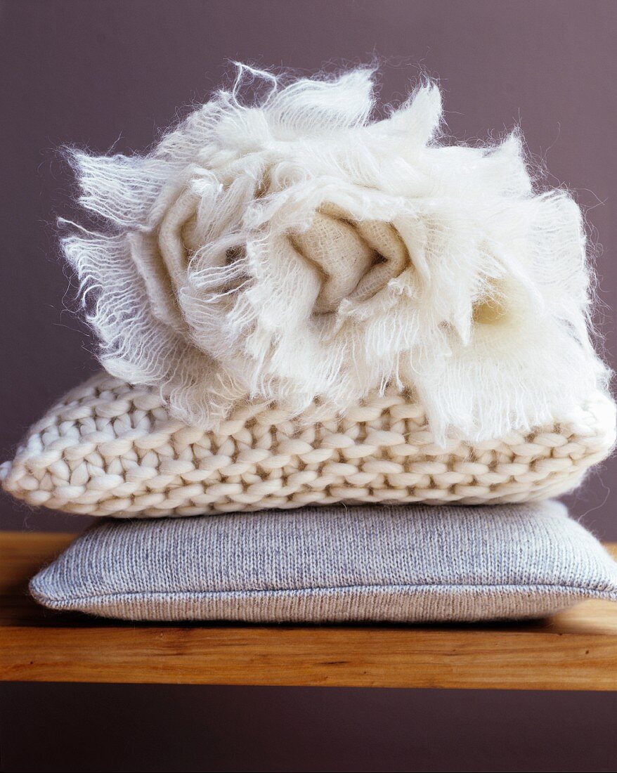 Cosy cushions and rolled, off-white blanket