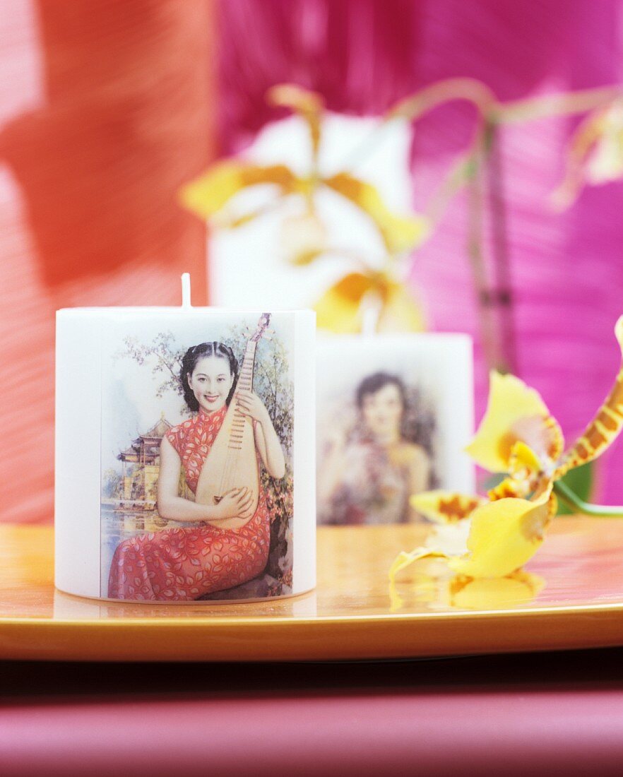 Motivkerzen mit asiatischer Frau und einer Pipa neben Orchideenblüte
