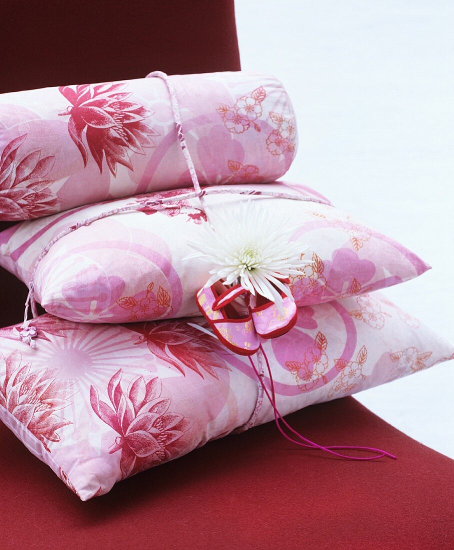 Stack of pink floral cushions decorated with dahlia and baby shoes