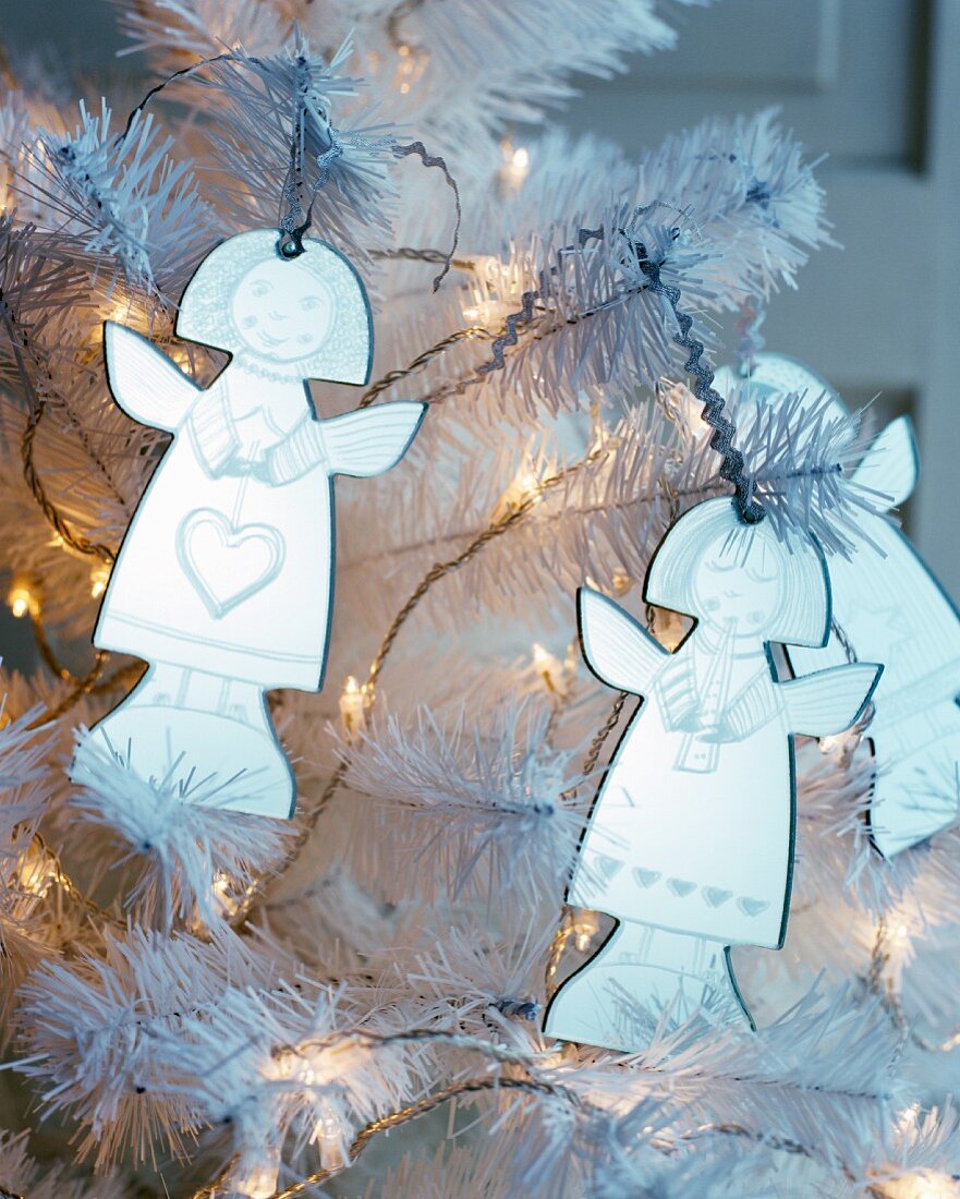 Engelsfiguren an weißem Kunstbaum mit Lichterkette