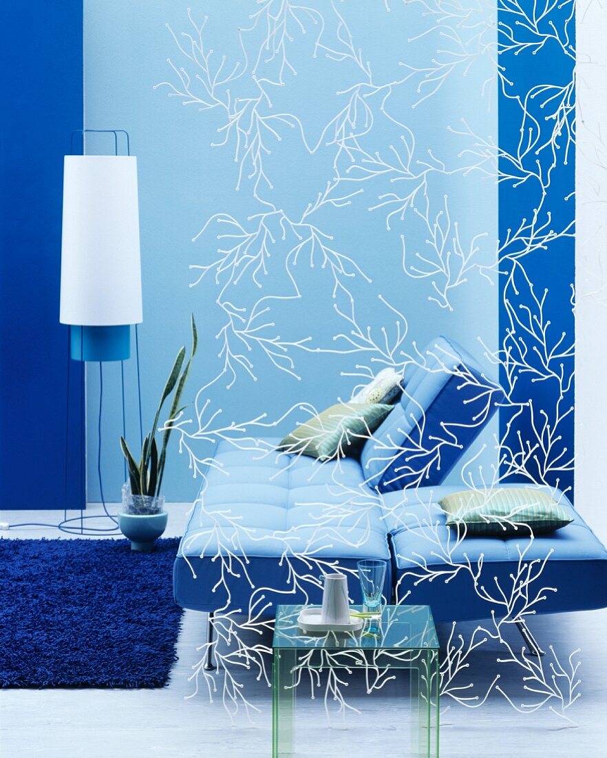 Blick durch filigranen Raumteiler auf Klappsofa vor blauer Wand