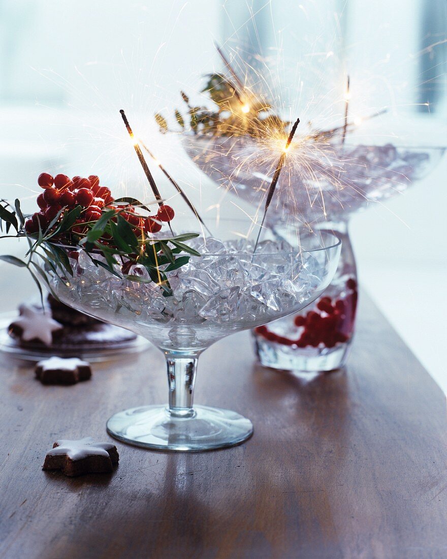 Glasschale mit Eiswürfeln, Beeren und Wunderkerzen