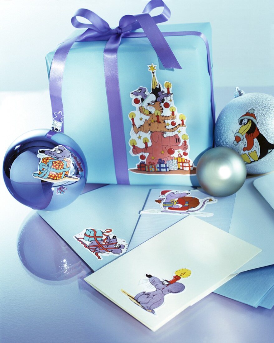 Arrangement aus Briefumschlägen, Weihnachtskugeln und verpacktem Geschenk, mit verschiedenen Cartoon-Motiven