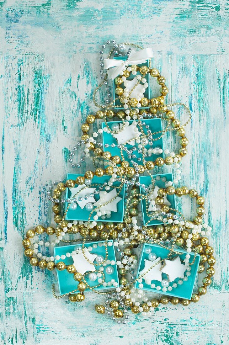 Türkise Schachteln und Perlenketten formen einen Weihnachtsbaum