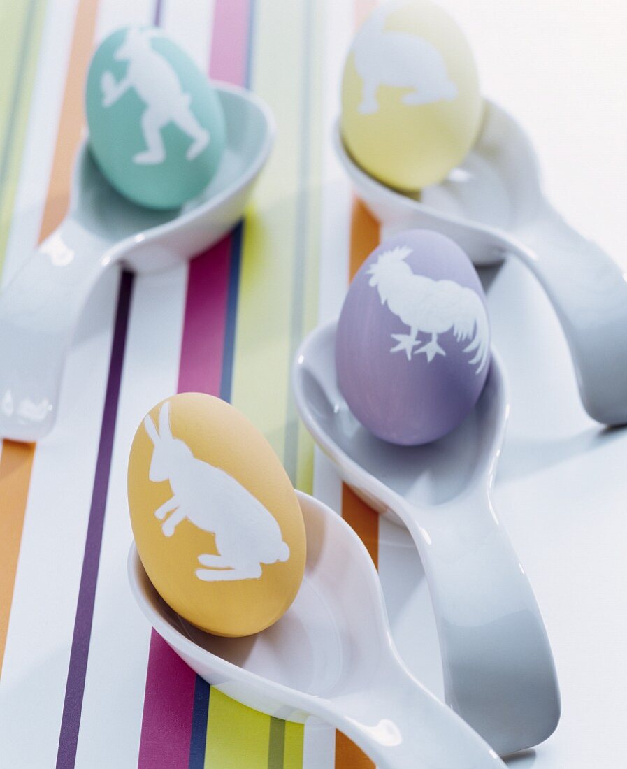 Dyed Easter eggs with various motifs arranged on china spoons