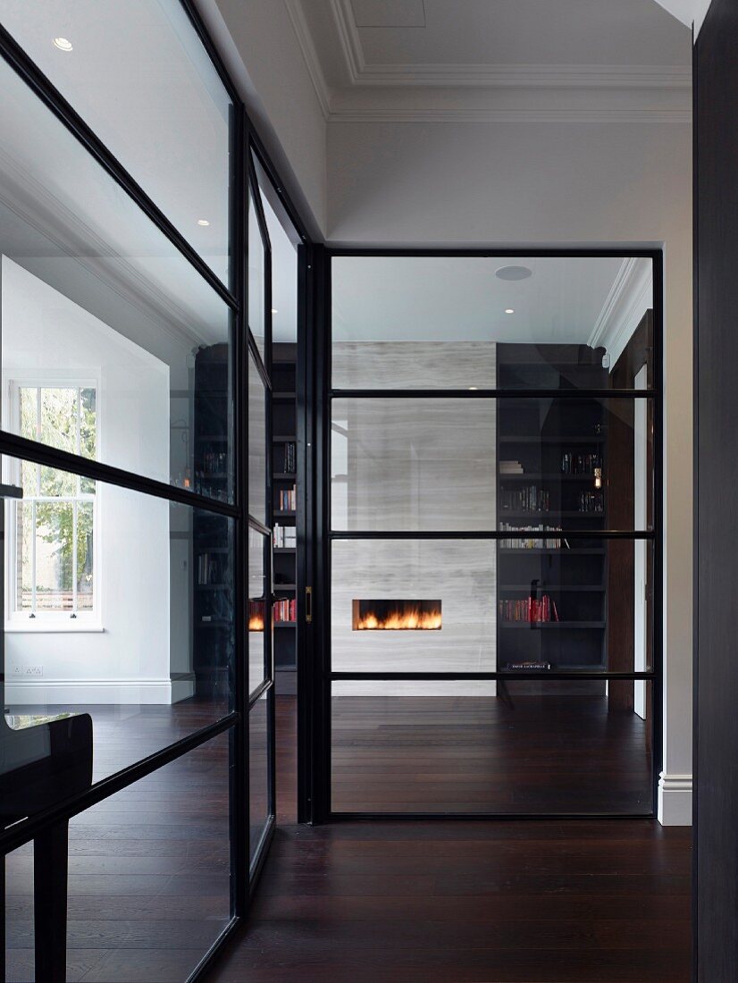 View of fire in fireplace seen through glass wall with black lattice structure
